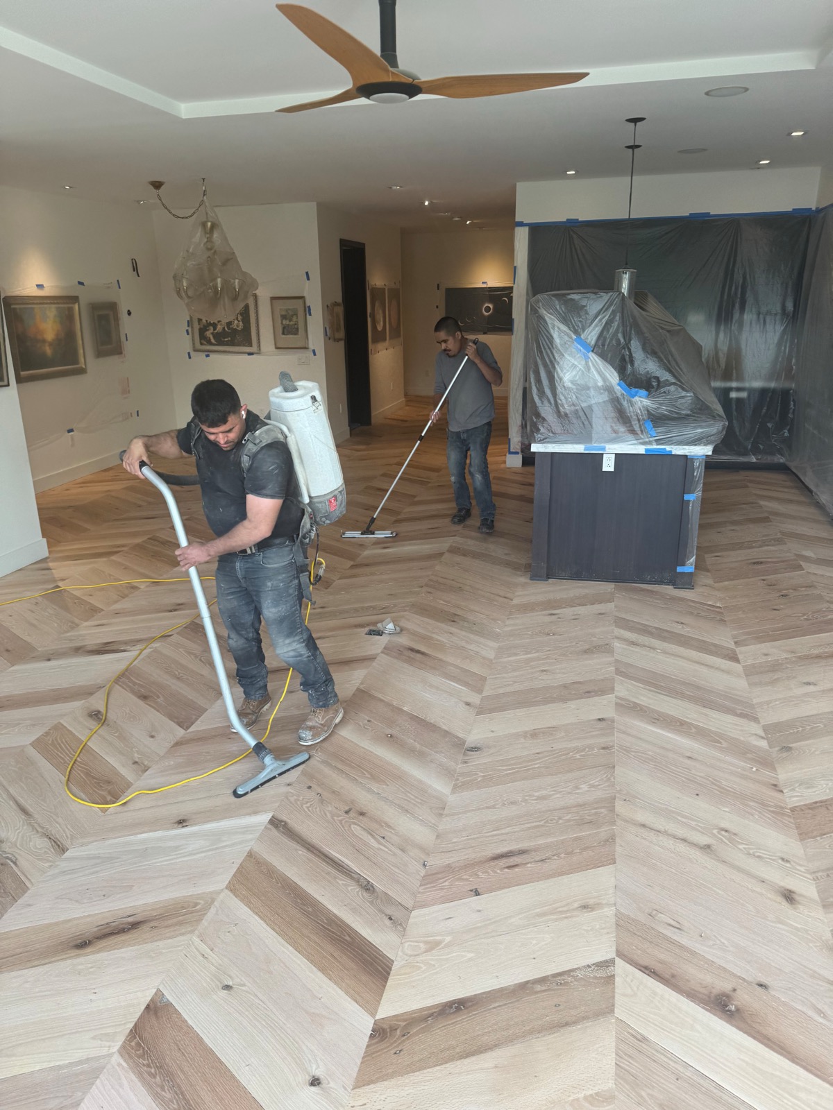 Crew vacuuming the chevron floor with dust-contained equipment after sanding
