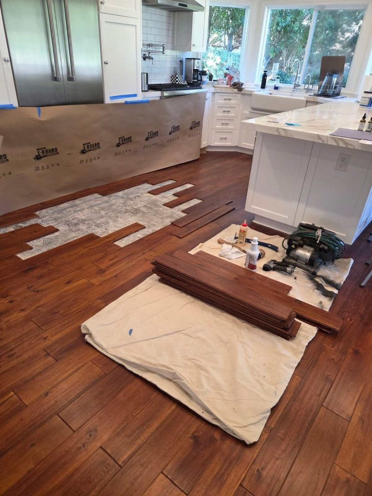 Hand-scraped walnut planks being installed in a bright white kitchen