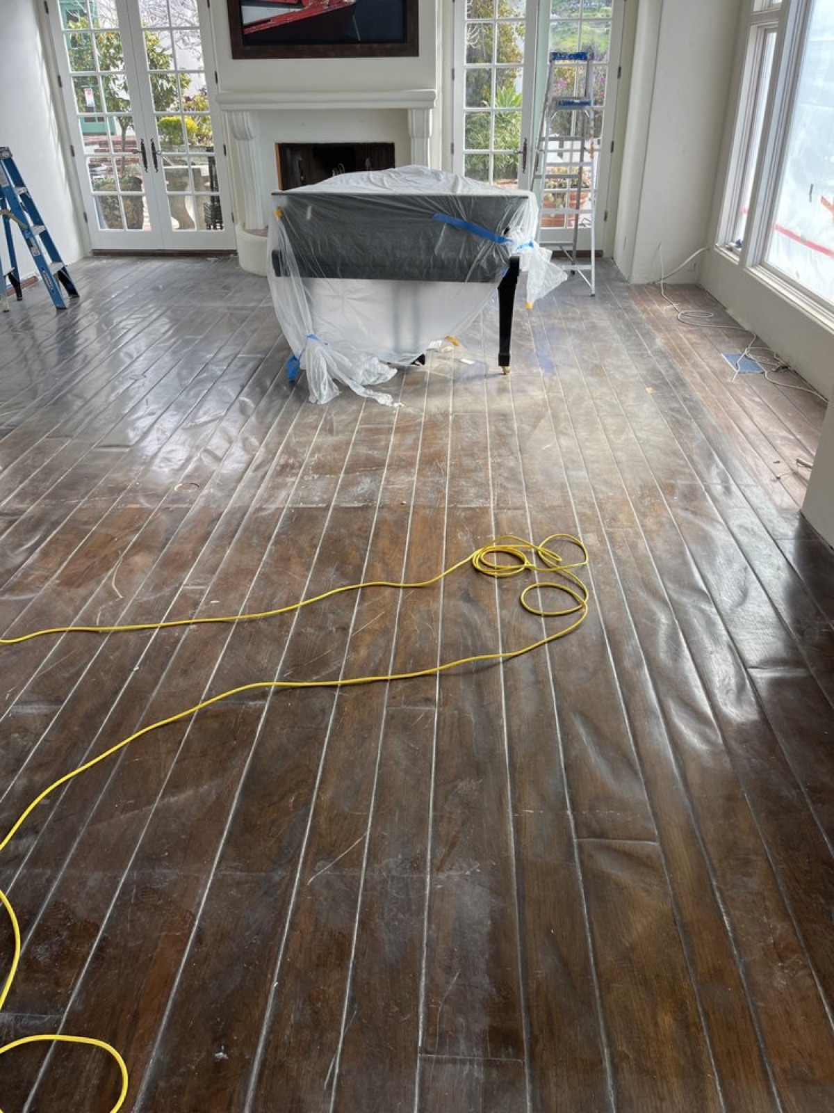 Living room floor stripped and prepped before staining, furniture protected