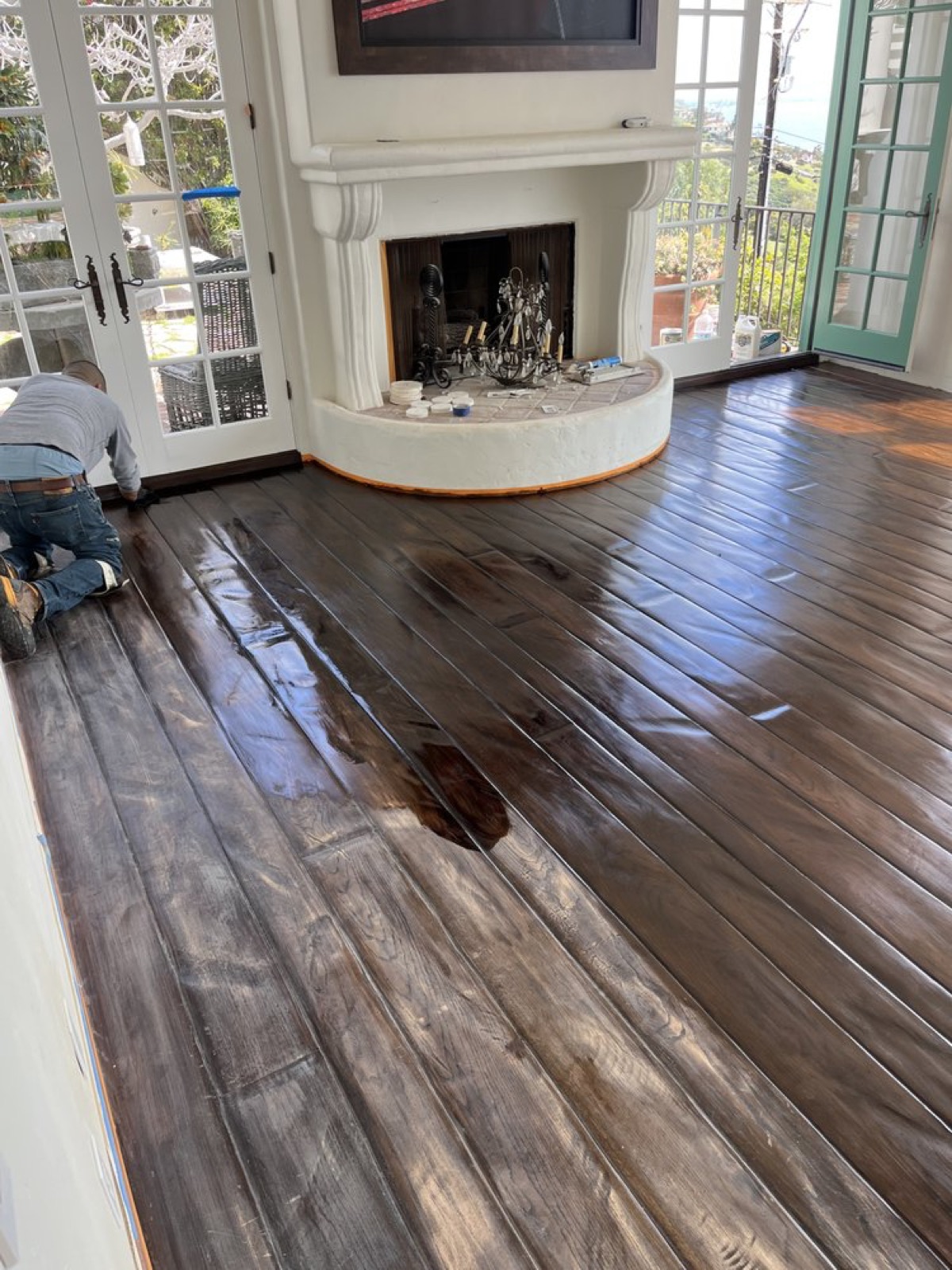 Atlantic craftsman kneeling to apply a rich dark stain during a floor refinish