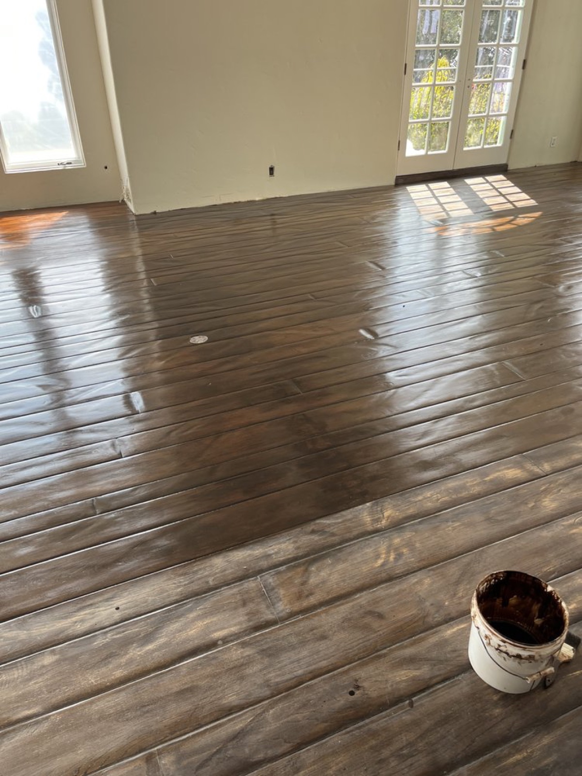 Freshly stained dark plank floor with wet finish catching the light